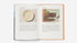 Open book with images of a ceramic plate and a room interior on a white background