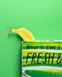 Yellow banana peeking out from a cookbook titled 'What to Cook & How' on a green background