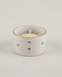 Speckled ceramic candle holder with a white candle on a light gray background