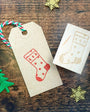 Christmas-themed stamp on a paper tag with decorative elements on a wooden surface