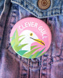Pink button with 'Clever Gull' logo on a denim jacket