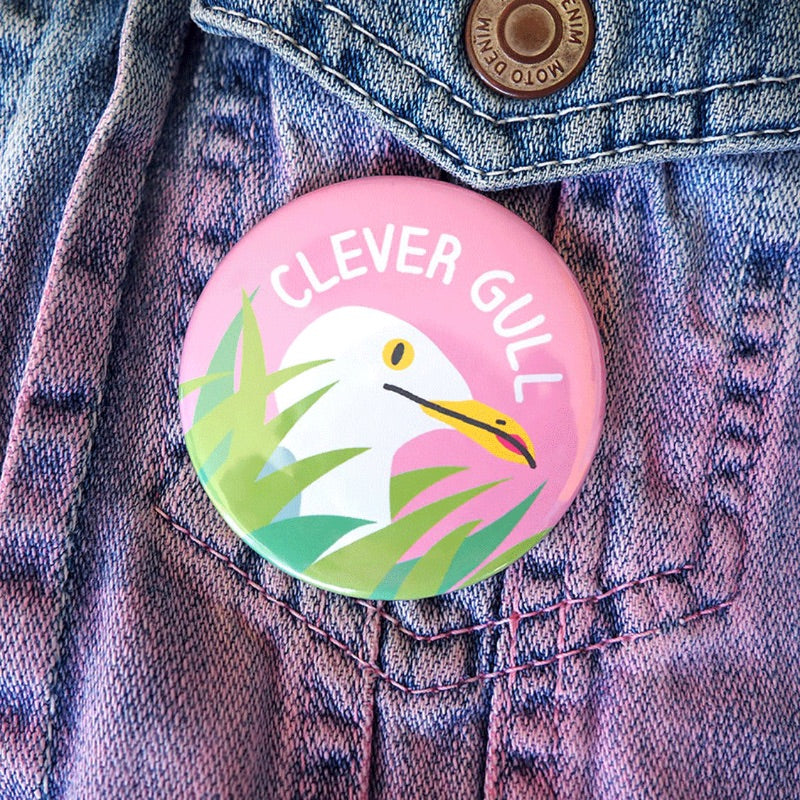 Pink button with 'Clever Gull' logo on a denim jacket