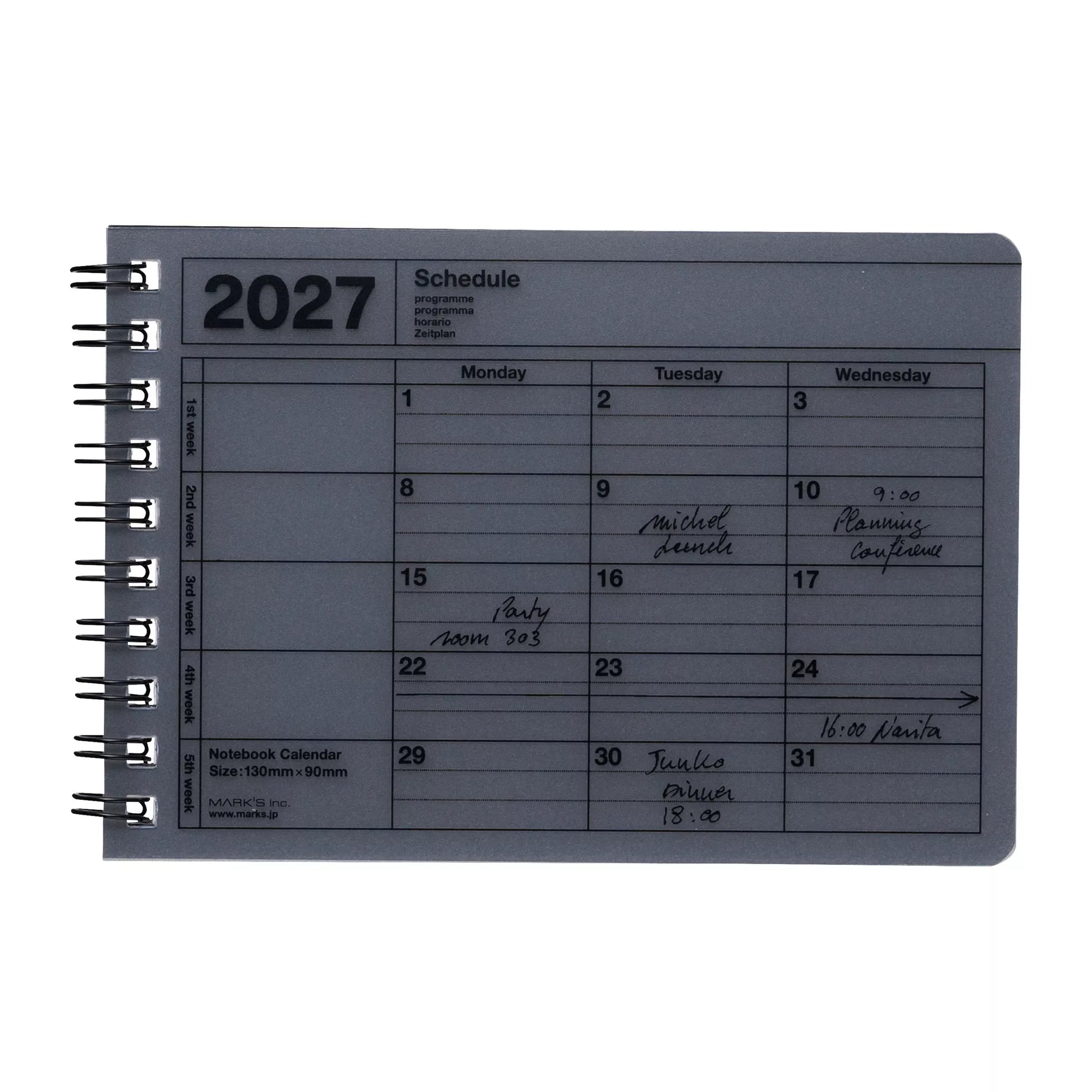 A 2027 spiral-bound notebook calendar on a plain white background. The cover is a muted gray-blue color with black printed text and grid lines, and the dates have been handwritten in black ink.