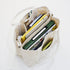Beige tote bag with compartments filled with books and office supplies on a white background
