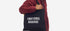 Person holding a black tote bag with 'EMOTIONAL BAGGAGE' text on a white background