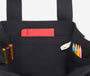 Black tote bag with colorful pens and a red pocket on a white background
