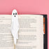 Ghost-shaped bookmark in an open book with a pink background