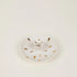 White ceramic plate with gold speckles on a light beige background