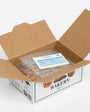 Open cardboard box with bakery branding, containing ice packs and an invoice on a white background
