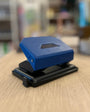 Blue and black hole puncher on a wooden surface with a blurred background