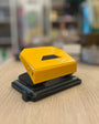 Yellow hole puncher on a wooden surface with a blurred background