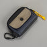 Small pouch with beige flap and black carabiner on a gray background