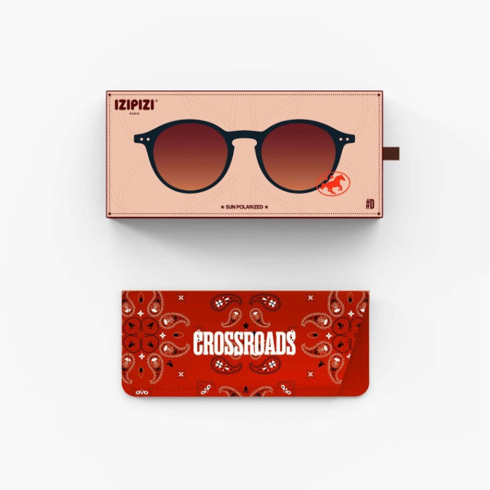 Two rectangular accessory boxes shown on a light gray background: the top box is pale peach with an illustration of round sunglasses and the brand name IZIPIZI; the bottom box is red with a paisley pattern and the word CROSSROADS. No person, animal, or real environment is present, so this is Product/Packaging.