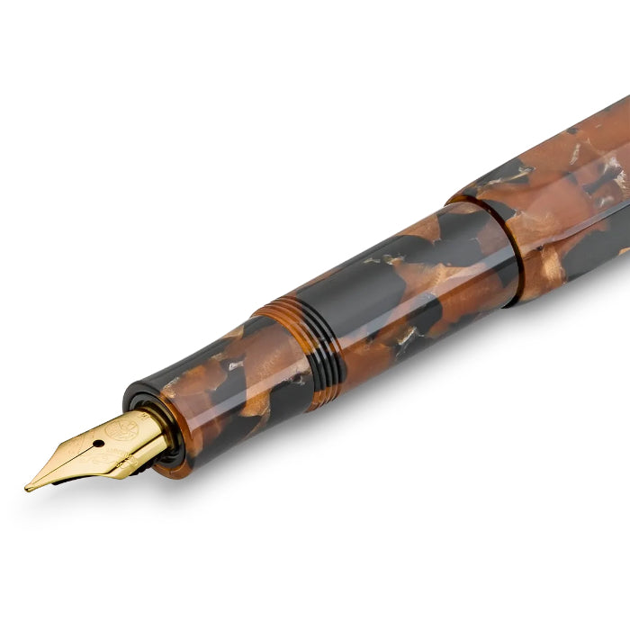 A close-up of a fountain pen nib and upper barrel showing a glossy tortoiseshell pattern in brown and black with a polished gold nib.