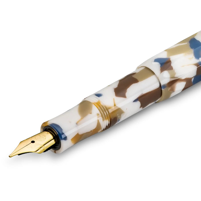 close up of kaweco fountain pen with a marbled resin body in white, gold, and navy blue, featuring a polished gold medium nib