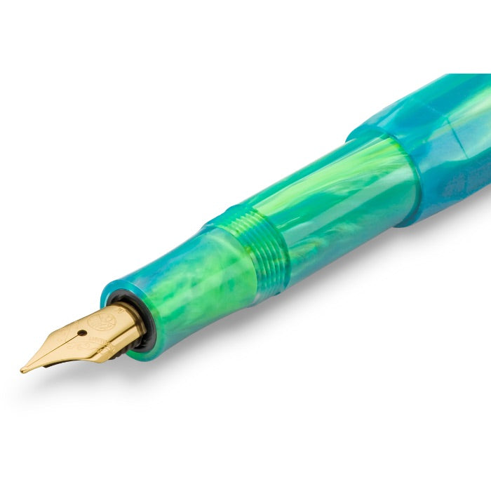A close-up of a fountain pen nib and upper barrel showing a translucent green and blue marbled resin finish with a gold nib.