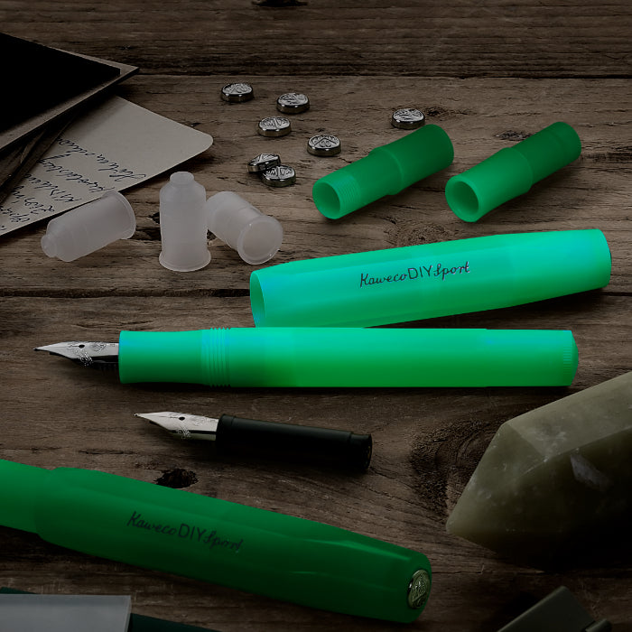 Green fountain pens and components on a wooden surface