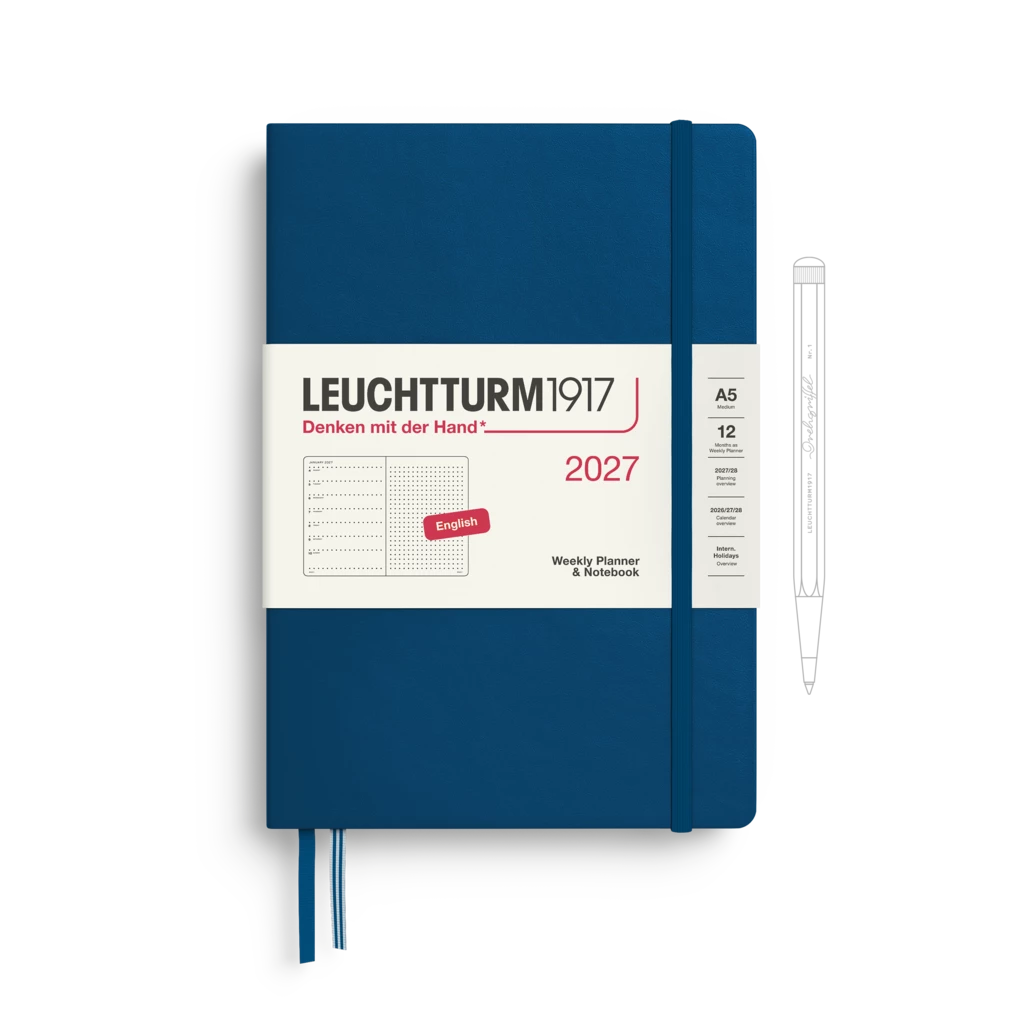 A Leuchtturm1917 2027 weekly planner and notebook in navy blue with a white paper band, shown alongside a white pen on a clean white background.