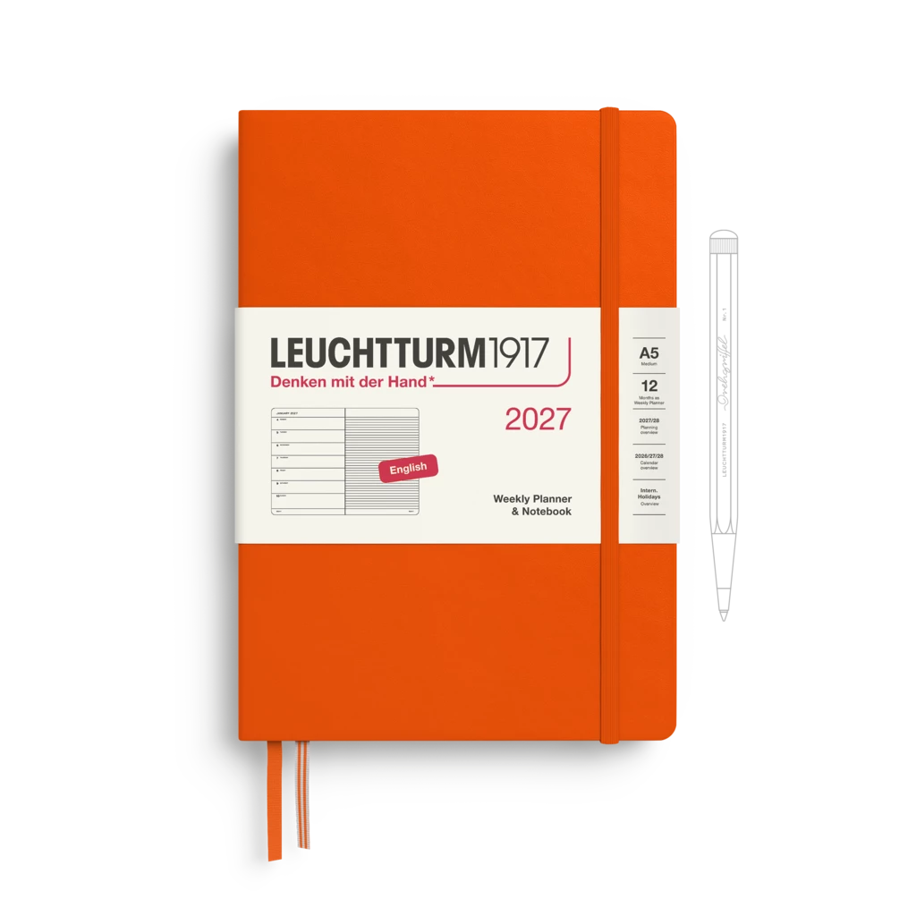 An orange Leuchtturm1917 2027 weekly planner and notebook with a white front label, shown closed with an orange ribbon bookmark. A white pen outline is visible to the right on a clean white background.