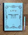 Blue notebook with decorative cover and a pen on a wooden surface