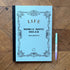 Blue notebook with decorative cover and a pen on a wooden surface