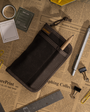 Black pouch on a newspaper background with stationery items