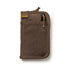 A pocket journal with a waxed canvas cover, displayed alongside a pen and cables, revealing the interior dot grid refill and organization pockets.