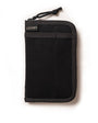 A pocket journal with a waxed canvas cover, displayed alongside a pen and cables, revealing the interior dot grid refill and organization pockets.