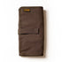 A partially unrolled tool roll with a brown waxed canvas exterior, aluminum hook fastener, and multiple pockets containing pens and other tools.