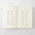 An open book or journal showing two cream-colored pages with printed calendar grids for 2017 and 2018 in gray text, photographed against a light gray background.