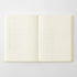 An open cream-colored notebook with lined pages, photographed flat against a light gray background.