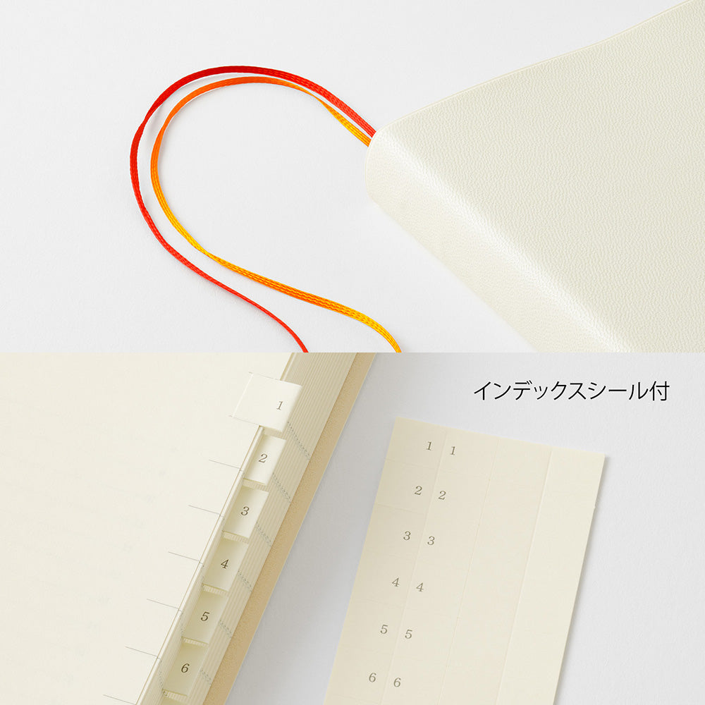 An off-white leather-bound notebook shown with its matching tabbed index page and numbered index stickers, featuring red and orange ribbon bookmarks on a clean white background.