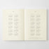 An open book or planner spread showing calendar pages for 2027 and 2028, with small monthly grids printed in gray on warm off-white pages, photographed against a light gray background.