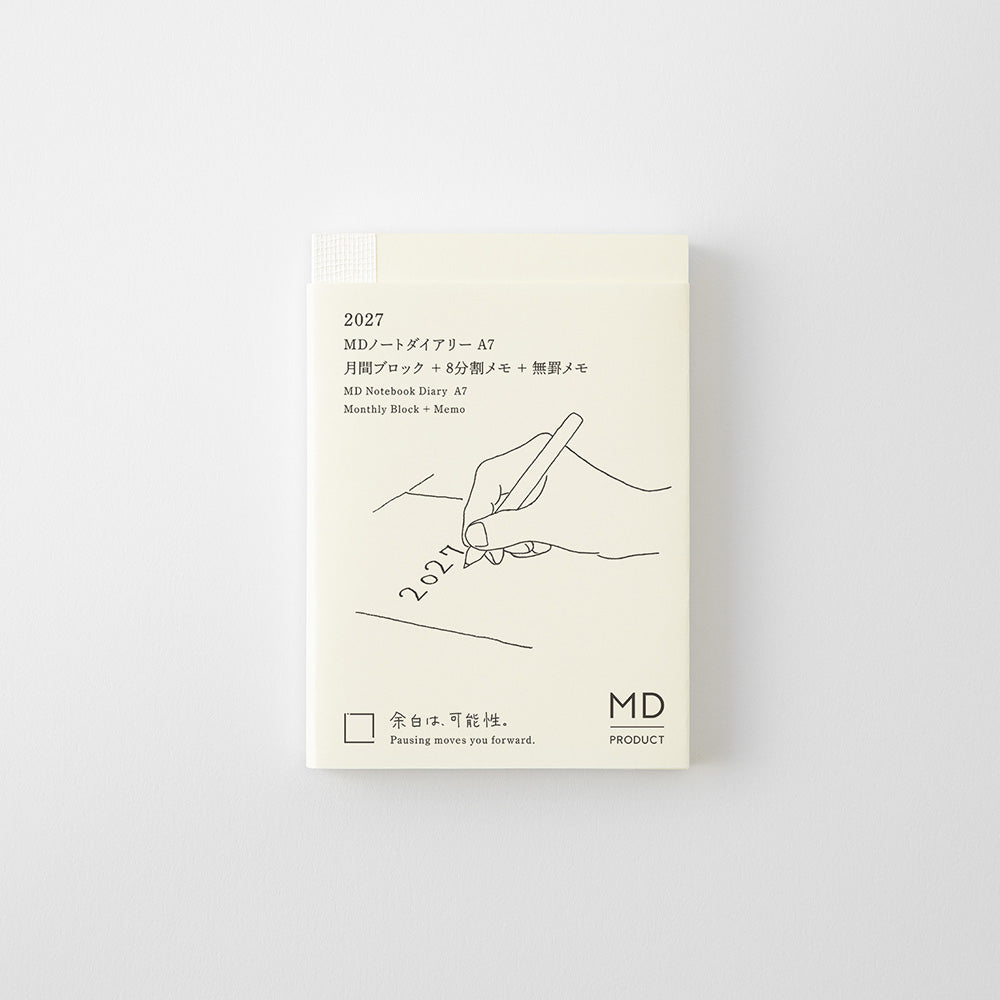 An A7 size monthly planning notebook by MD Product, featuring a minimalist cream cover with black line art of a hand writing and Japanese text.