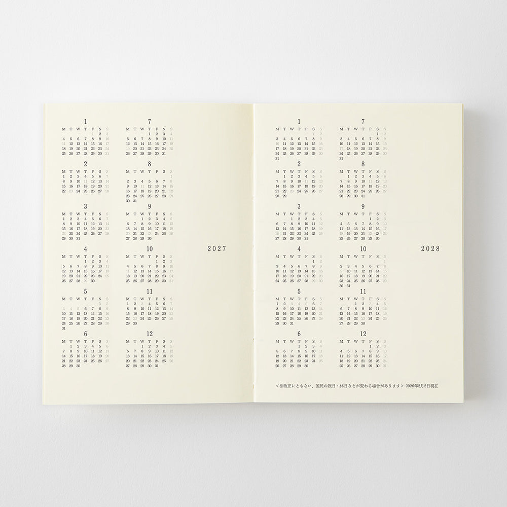 An open cream-colored planner or calendar showing printed monthly calendar grids for 2017 and 2026 on both pages, photographed against a light gray background.