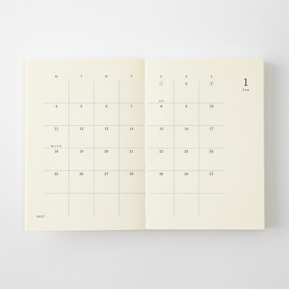 An open cream-colored planner or journal showing two monthly calendar spreads for January, photographed against a clean white background.