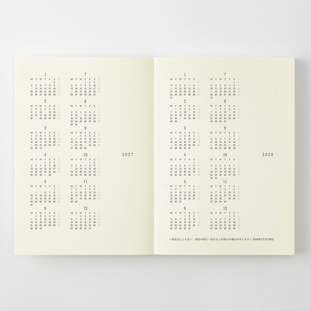 An open cream-colored book or planner showing printed calendar pages for 2027 and 2018 in gray text, photographed against a light gray background.