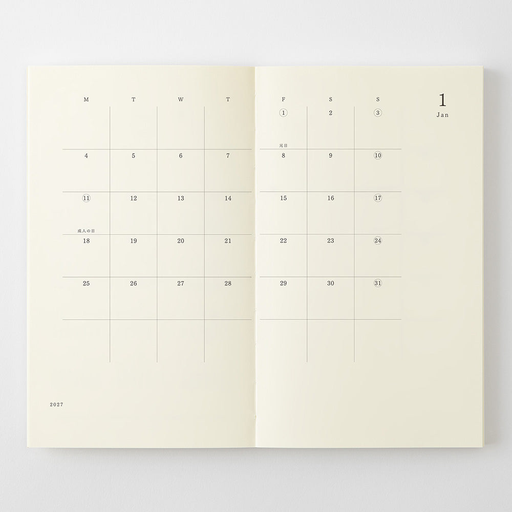 An open planner or journal showing two cream-colored interior calendar pages with minimalist black printed dates and weekday grids, photographed against a light gray background.