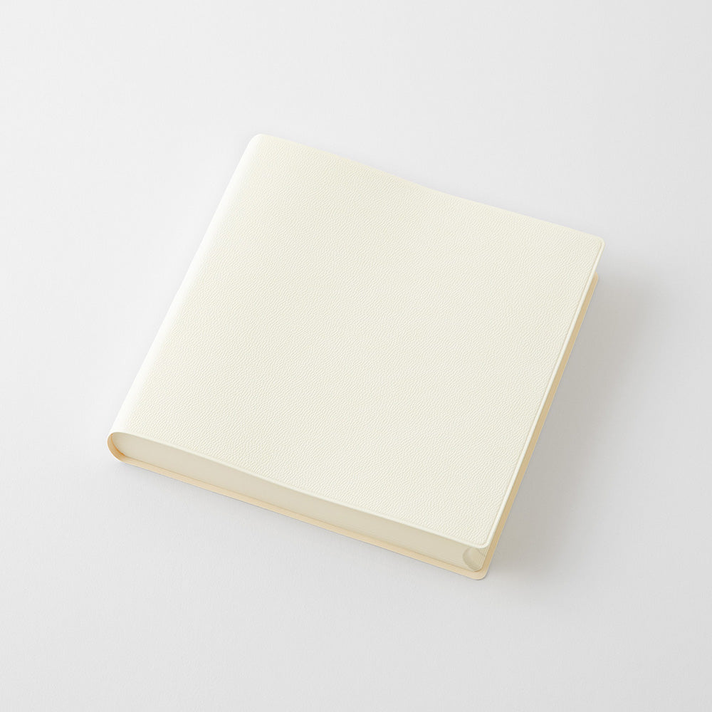 A blank cream-colored square photo album or notebook with a hard cover, shown at an angle on a light gray background.