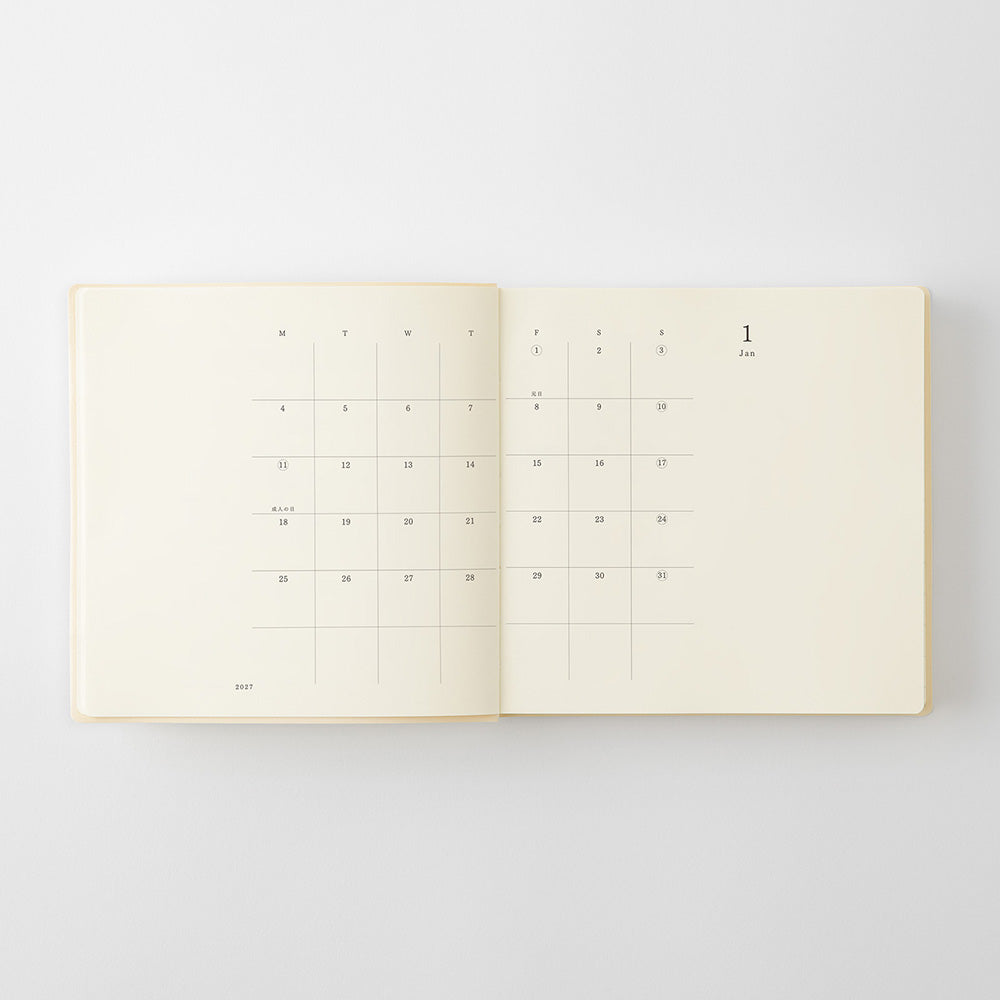 An open cream-colored planner or journal showing a minimalist monthly calendar grid on the left page and the date '1 Jan' on the right page, photographed against a light gray background.
