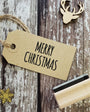 Kraft paper tag with 'Merry Christmas' text on a wooden surface with decorative elements.