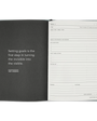 Open planner with a quote on the left page and a goal-setting layout on the right.