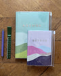 Two agendas with colorful covers on a wooden surface, accompanied by a pen and ruler.