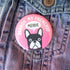 Pink button with a dog illustration and text on a denim background