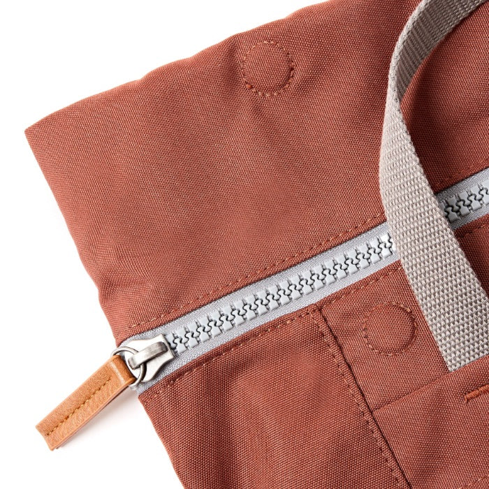 Close-up of a brown fabric bag with a silver zipper on a white background