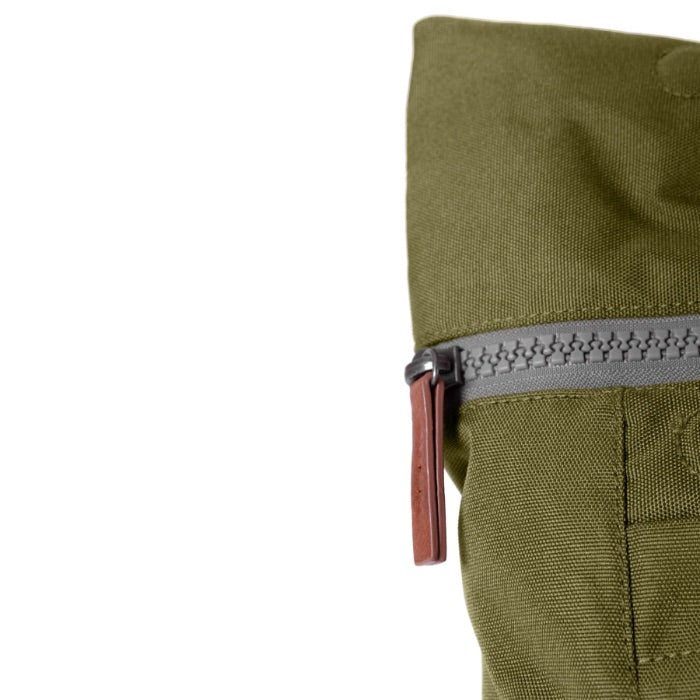 zip close up of moss coloured backpack in front of a white background