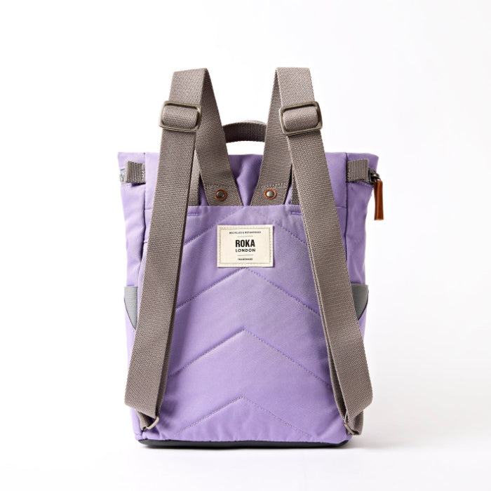 lavender coloured backpack on a white background with grey straps showing