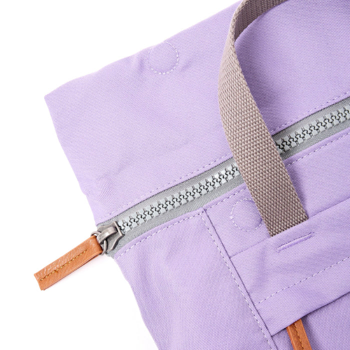 Close-up of a purple bag with a zipper and brown handle on a white background