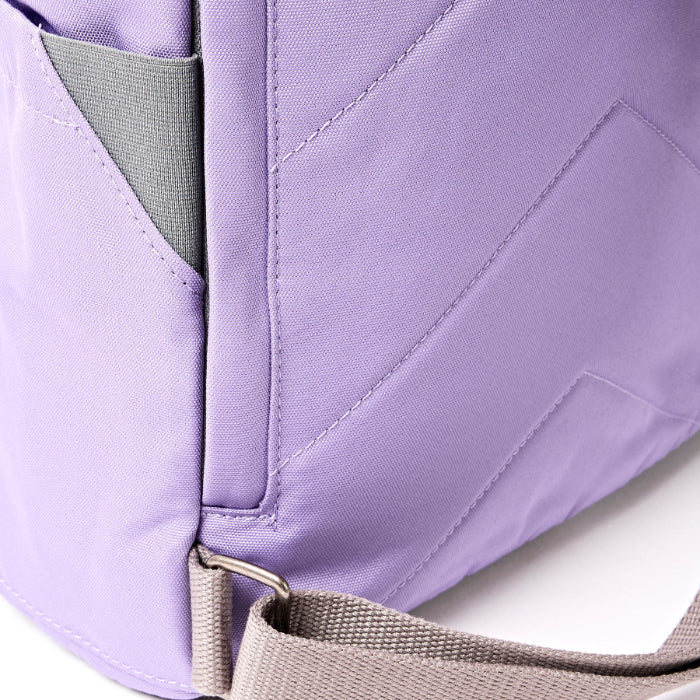 close up shot of lavender coloured backpack showing straps on a white background