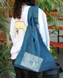 Person wearing a blue mesh bag over their shoulder in an outdoor setting with plants and furniture.